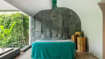 Un dormitorio moderno con una pared de piedra, una colcha color turquesa y una mesita de noche de madera.