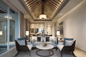 A modern living room with a sofa, two armchairs, a coffee table, and a dining area in the background.