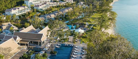 An aerial view of a resort with multiple buildings, a swimming pool, and a beach.