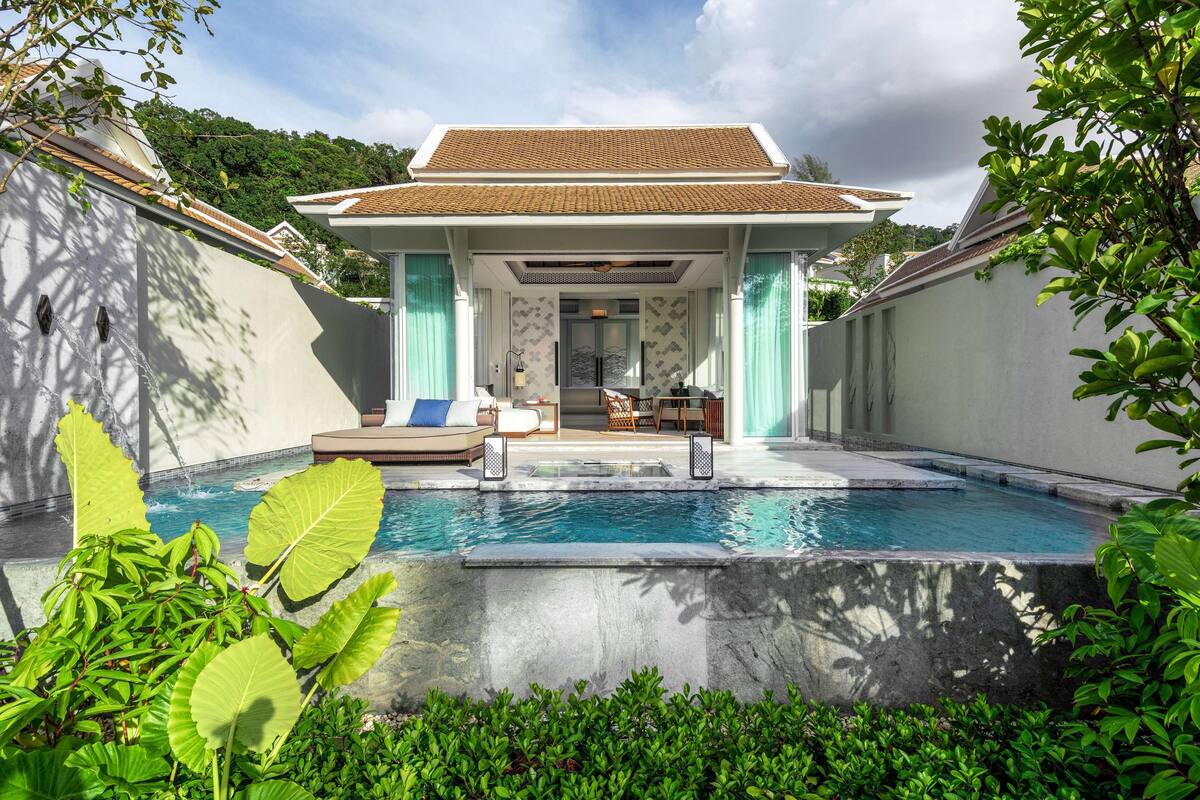 A modern house with a swimming pool, a covered patio, and lush greenery.