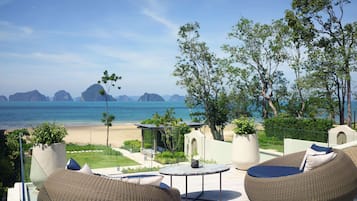 Relax in a serene outdoor space with ocean views, wicker chairs, and a round table.