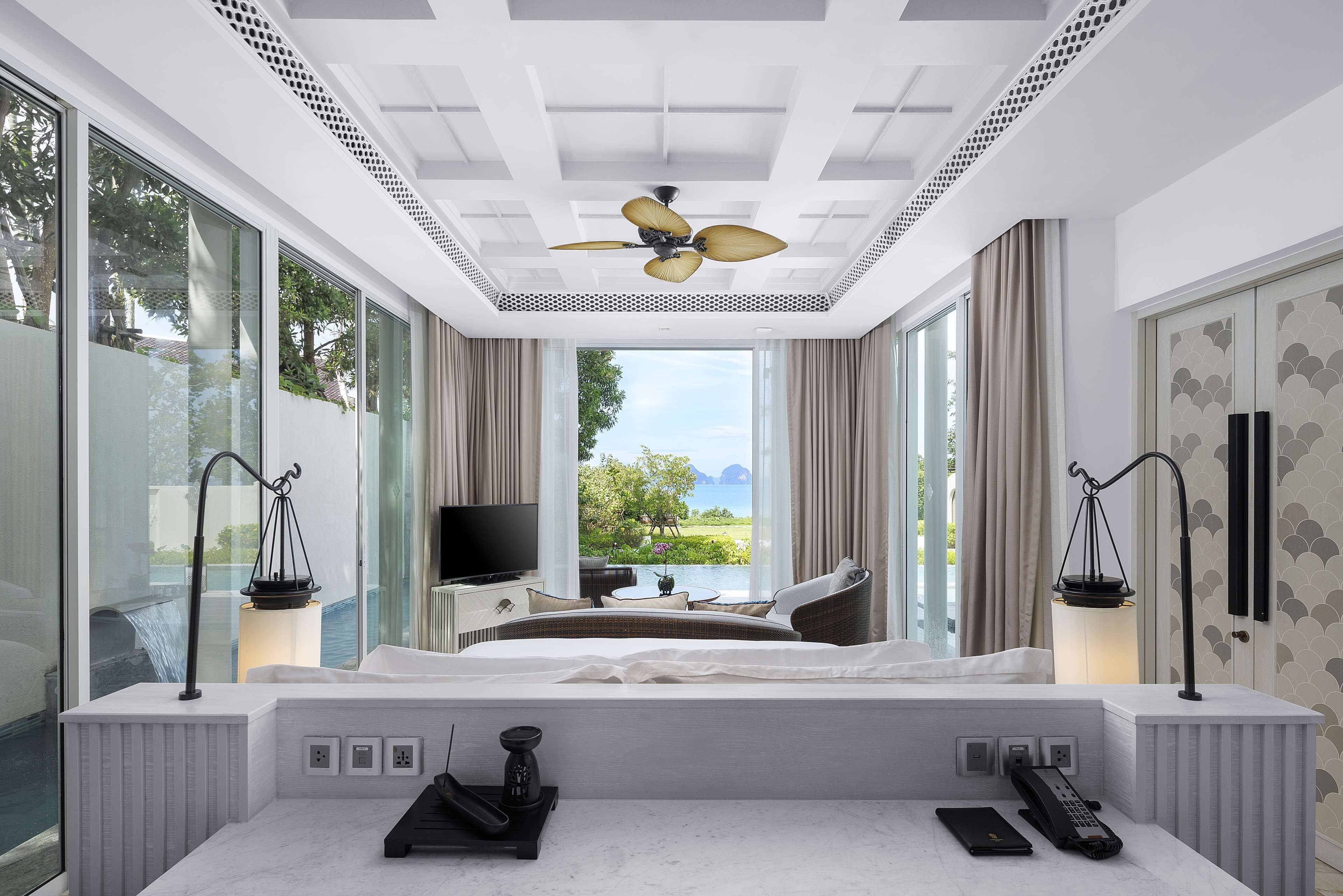 Habitación de hotel moderna con una cama grande, televisión, escritorio y vistas al exterior.