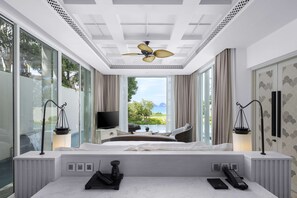 A modern hotel room with a large bed, a television, a desk, and a view of the outdoors.