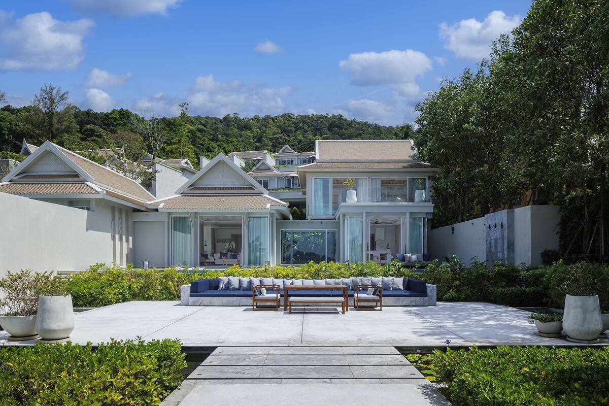 A modern house with a spacious patio, a large seating area, and a view of a lush green hillside.