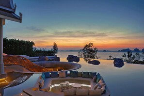 A luxurious infinity pool with a curved edge, surrounded by outdoor seating and a waterfall feature. - Banyan Tree Krabi (Krabi)
