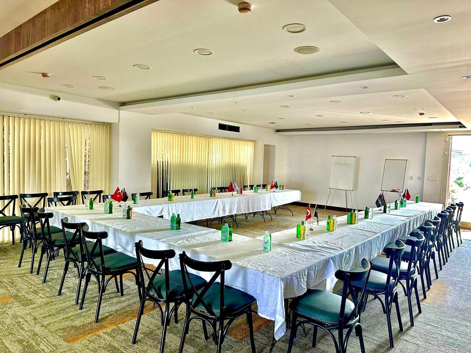 Une salle de conférence équipée de longues tables, de chaises et d’un tableau blanc.
