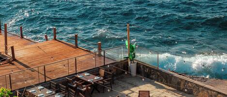 Un restaurant en bord de mer avec une terrasse offrant une vue sur l’océan.