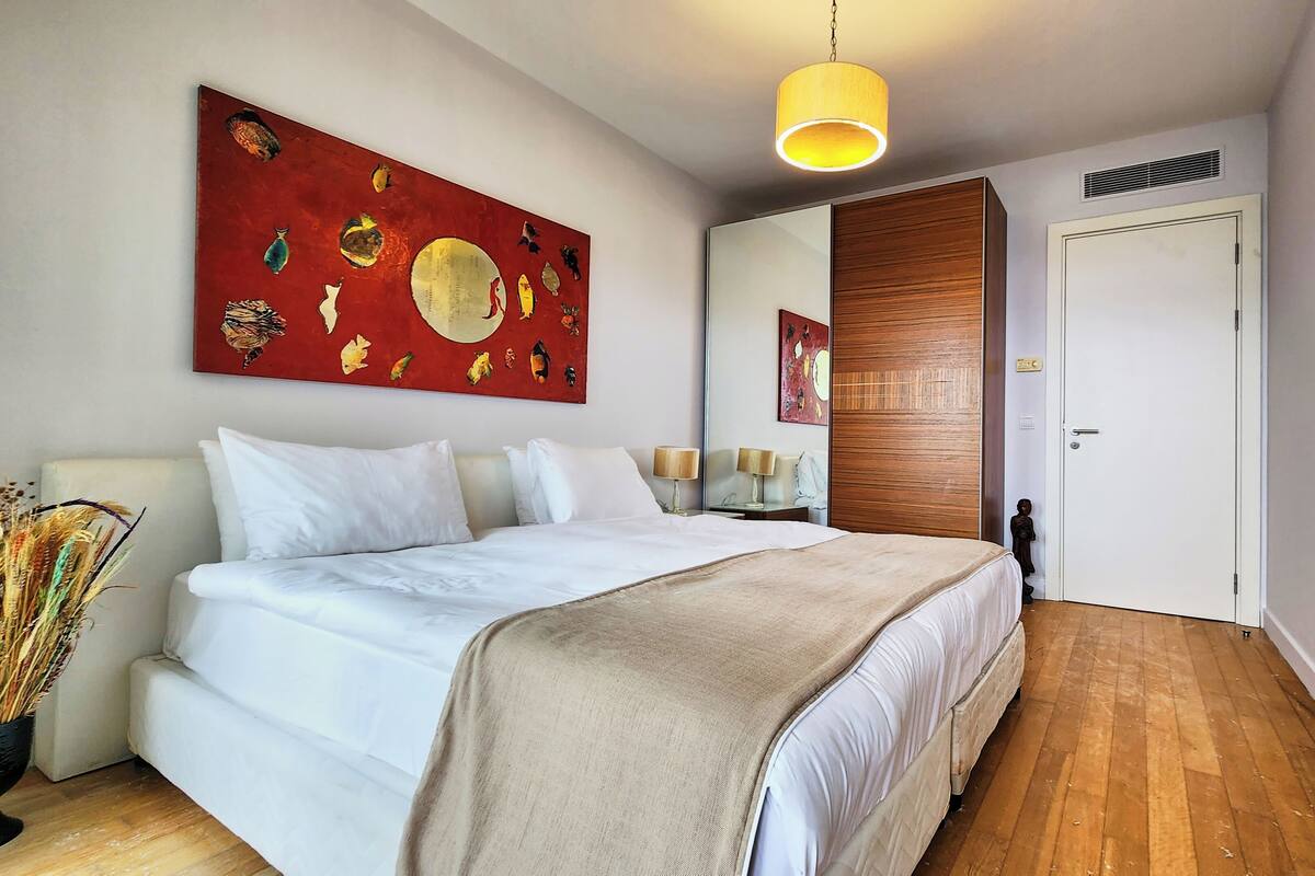 Un dormitorio con una cama grande, un espejo, un panel de pared de madera y una lámpara en el techo.