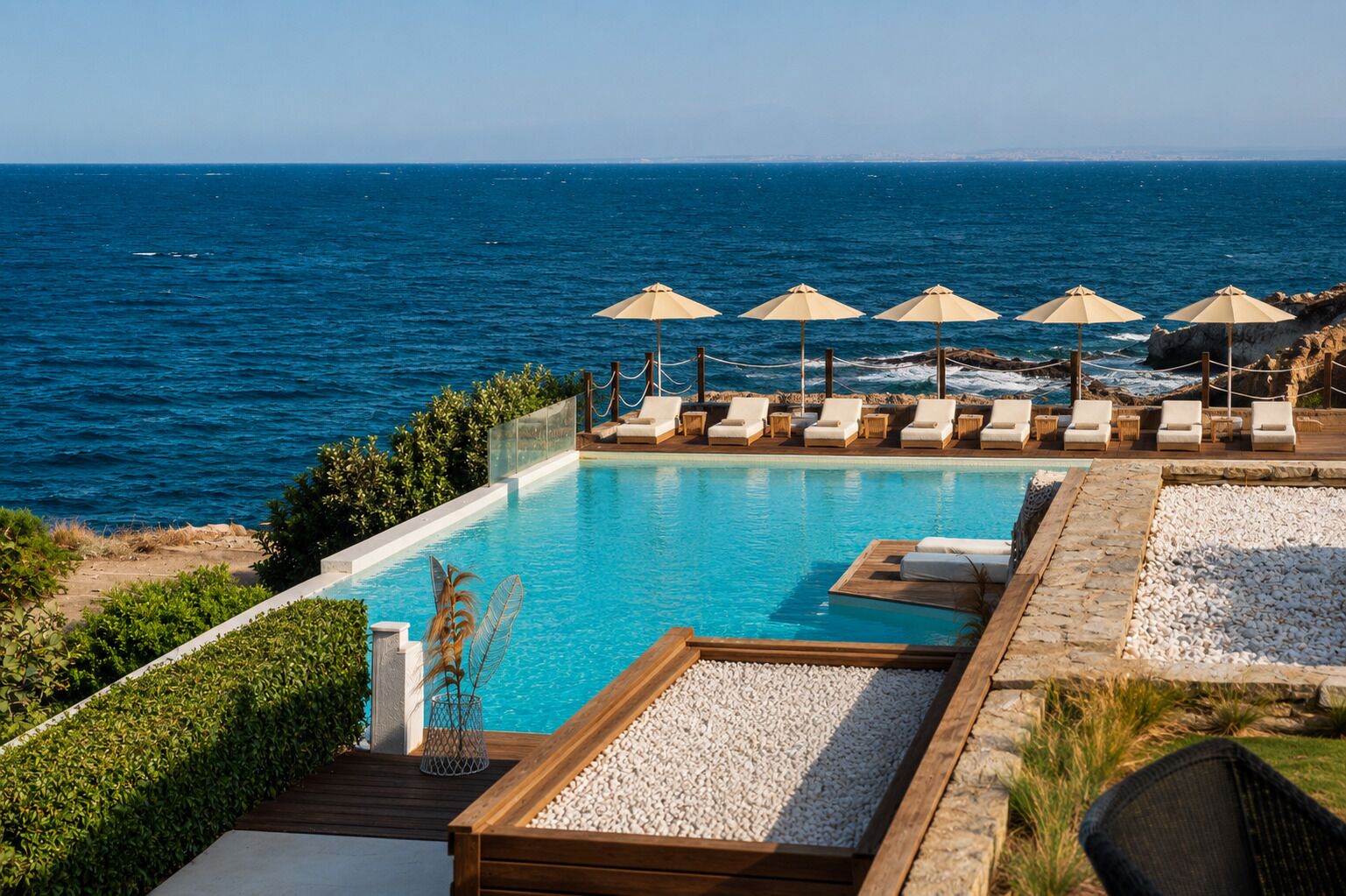 Une piscine avec des chaises longues et des parasols, donnant sur la mer.