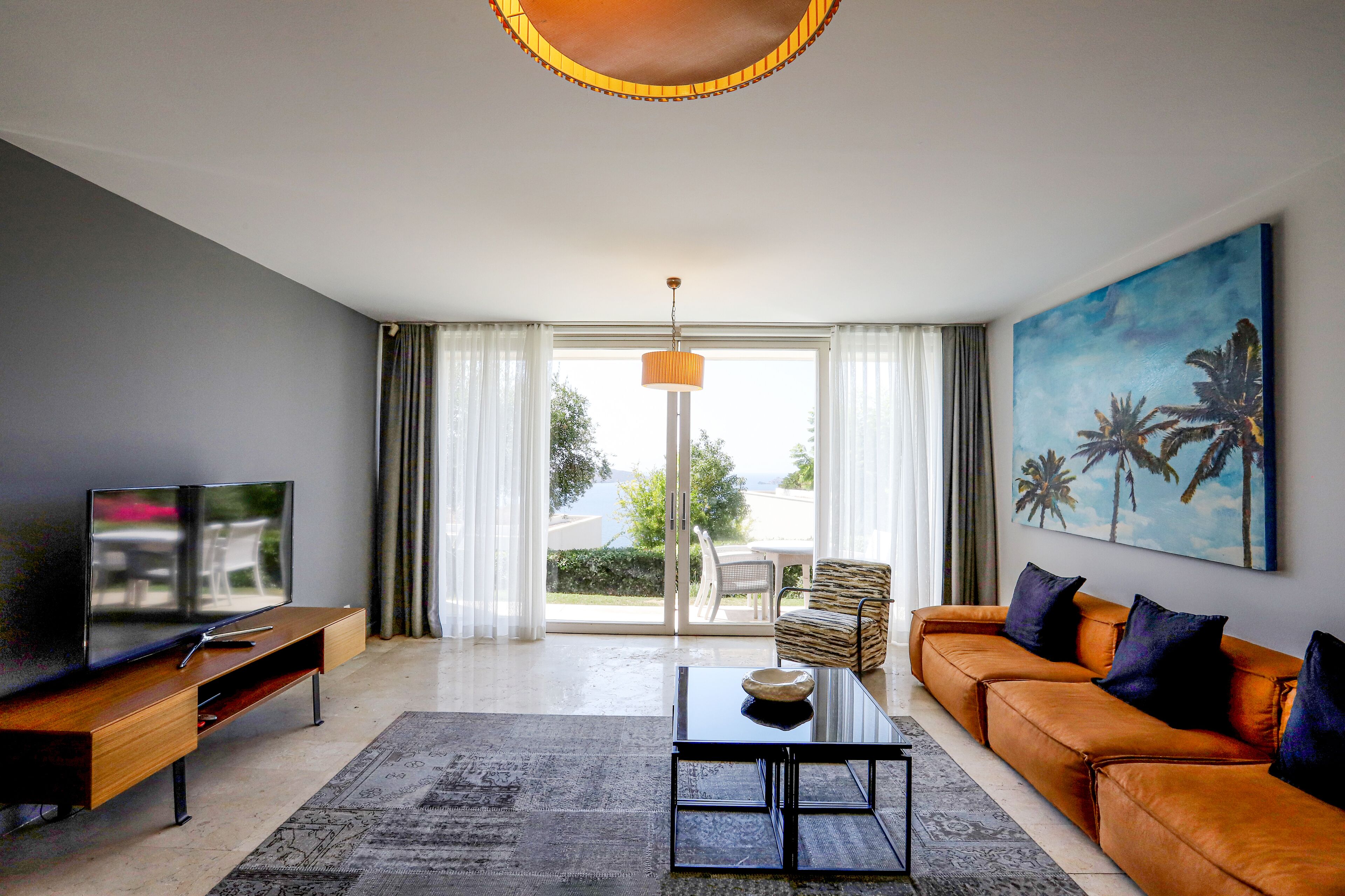 A modern living room with a sofa, TV, and artwork.