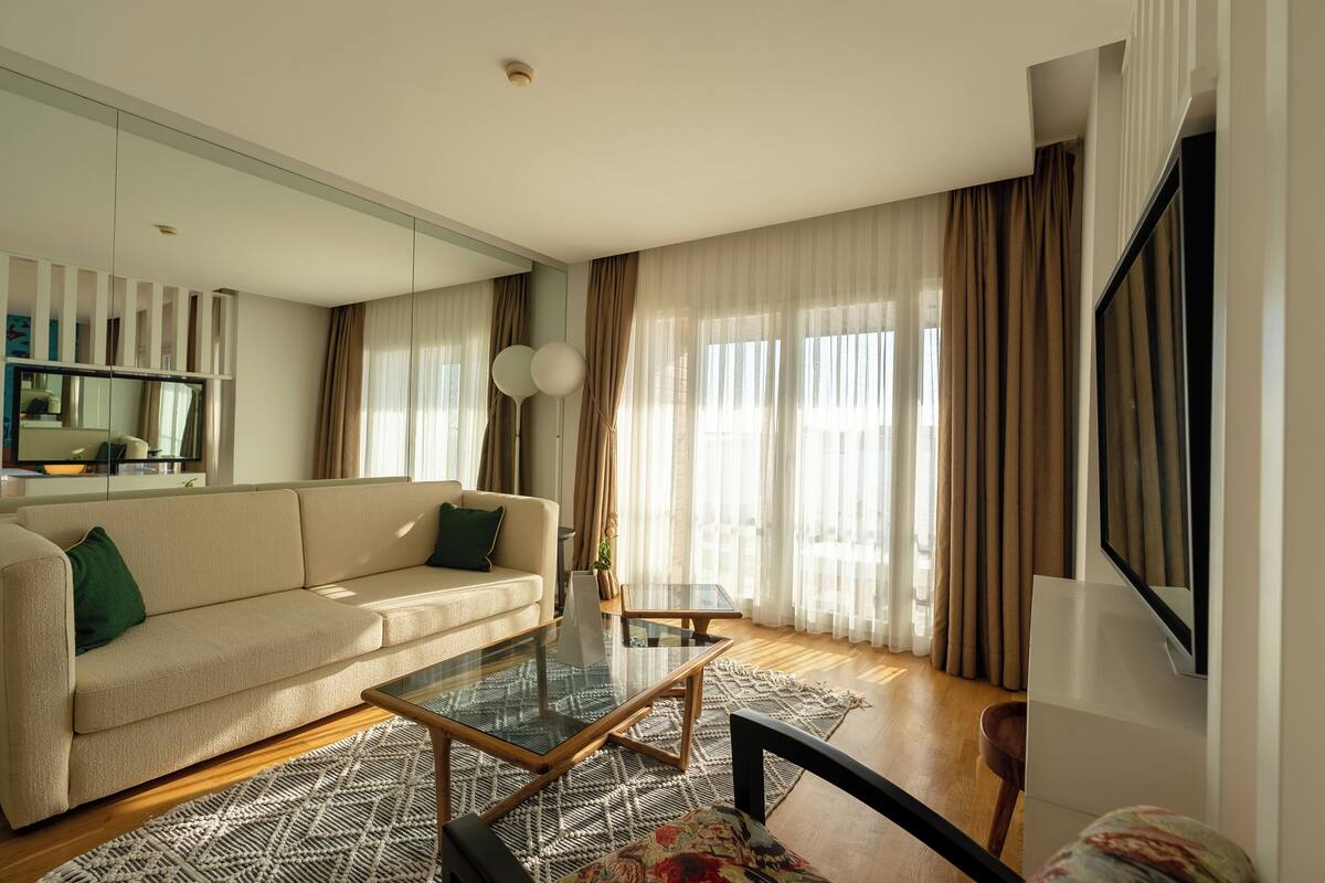 Una sala de estar moderna con sofá, mesa de centro de vidrio y un espejo grande.