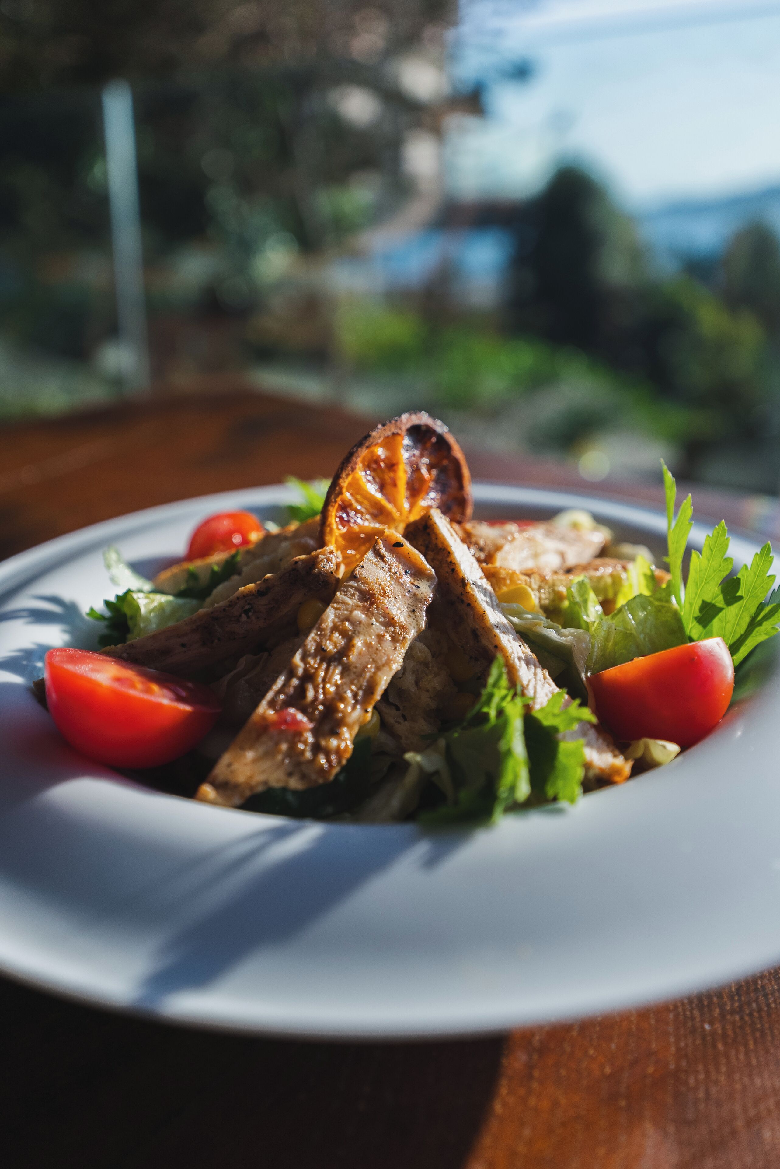 A plate of grilled meat with vegetables on a white plate.