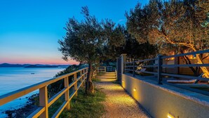 A pathway leading to a beach with a railing on one side and a wall on the other, under a twilight sky. - Mobile Home Pecten 04 (Pakostane)