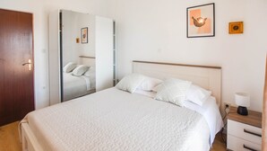 A neatly arranged bedroom with a bed, bedside table, and a mirror. - Apartments Anchor (Pasman)