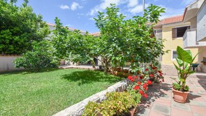 A courtyard with a stone wall, potted plants, and a tiled floor. - Apartments Anchor (Pasman)