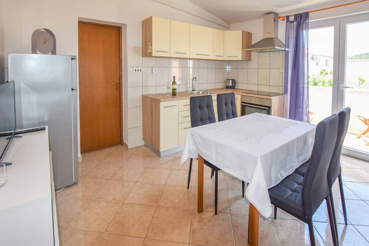 Cocina compacta con comedor, que incluye un refrigerador, armarios y una mesa preparada para dos personas.