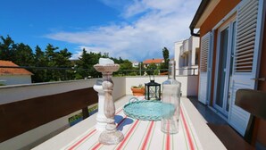 A balcony with a striped tablecloth, a candle holder, a lantern, and a glass bottle. - Apartments Skoda II (Novalja)