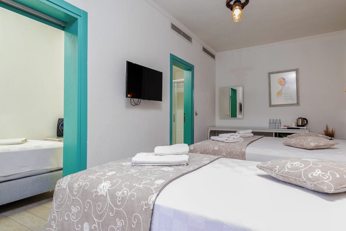 A hotel room with two beds, a flat-screen TV, a desk with a mirror, and a stone accent wall.