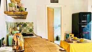 A modern kitchen with a wooden dining table, hanging shelves, and a black refrigerator.