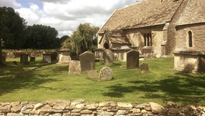 A stone church with a grassy cemetery in front.