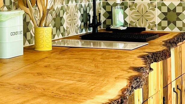 A kitchen with a unique wooden countertop featuring a natural edge.
