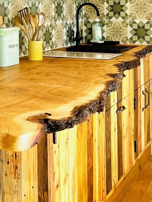 A kitchen with a unique wooden countertop featuring a natural edge.