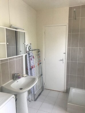 Een bad/douchecombinatie, handdoeken, toiletpapier