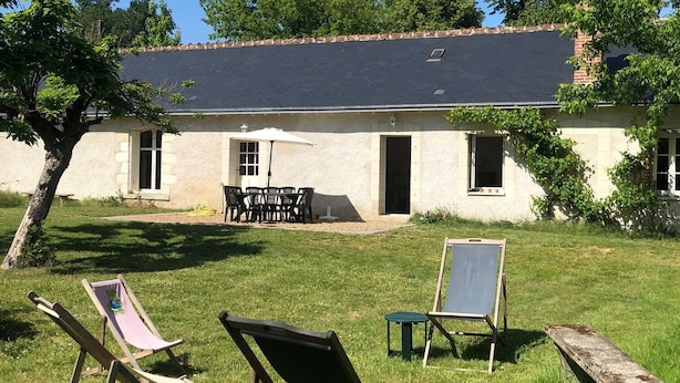 Een huis met een patio, een tafel en twee tuinstoelen.