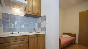 Une petite pièce compacte comprenant un coin cuisine, un lit et une porte en bois.