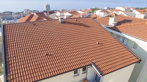 Un bâtiment doté d’un toit recouvert de tuiles rouges et d’un balcon agrémenté de mobilier d’extérieur.