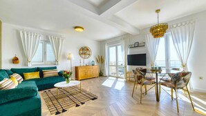 Ein modernes Wohnzimmer mit einem grünen Sofa, einem Couchtisch und einem Essbereich mit Stühlen.