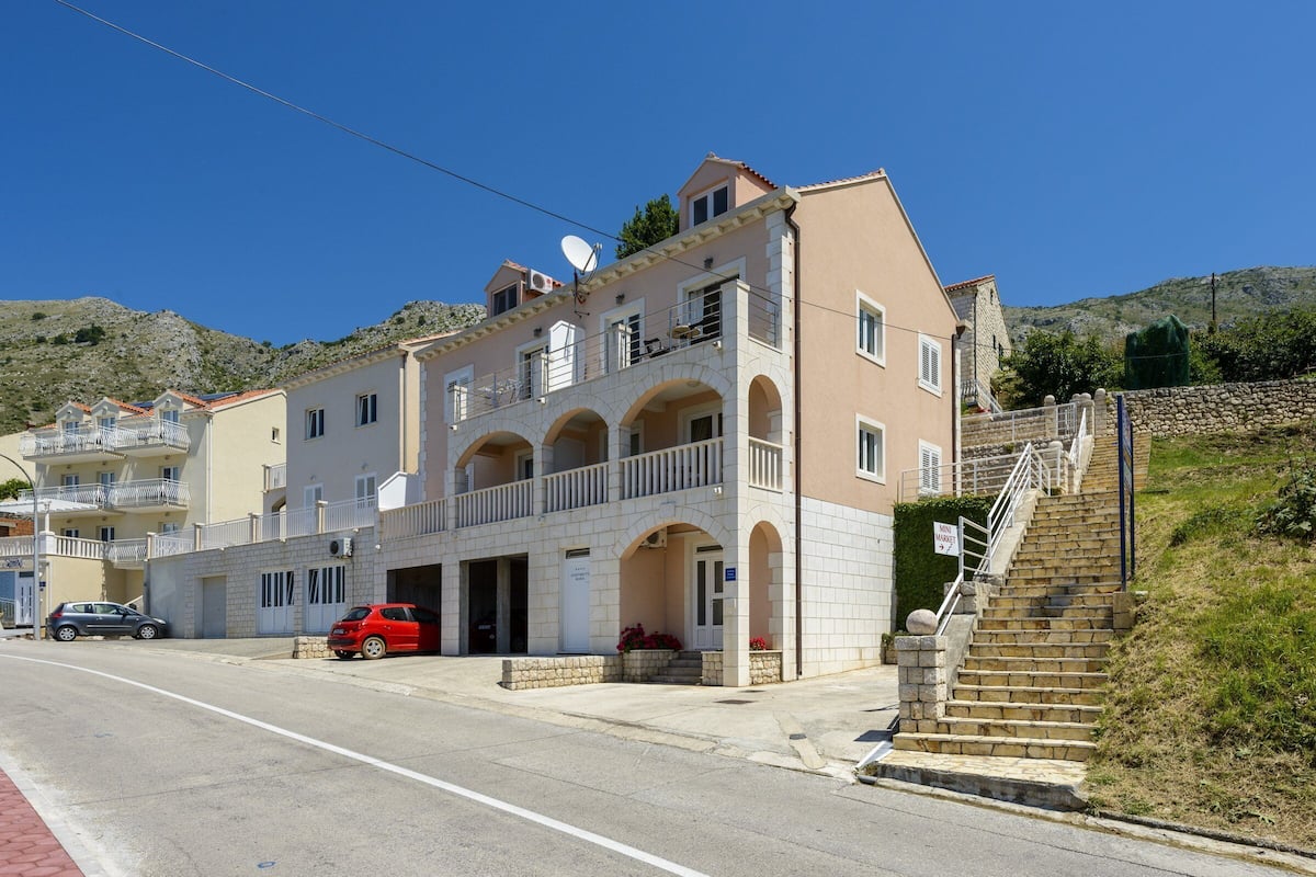 A multi-story building with a balcony, a staircase, and a parked car.