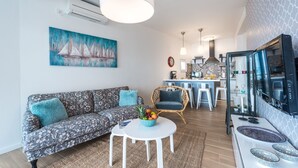 Ein modernes Wohnzimmer mit einer Couch, einem Essbereich mit Tisch und einer Küche mit Fernseher.