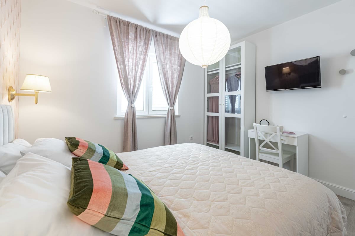 A bedroom with a bed, a desk, a TV, and a wardrobe.