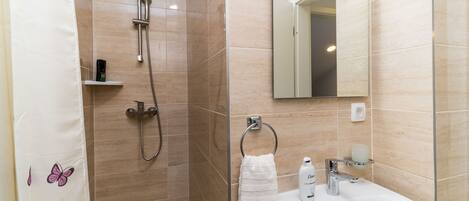 Ein Badezimmer mit Dusche, Waschbecken und Spiegel.