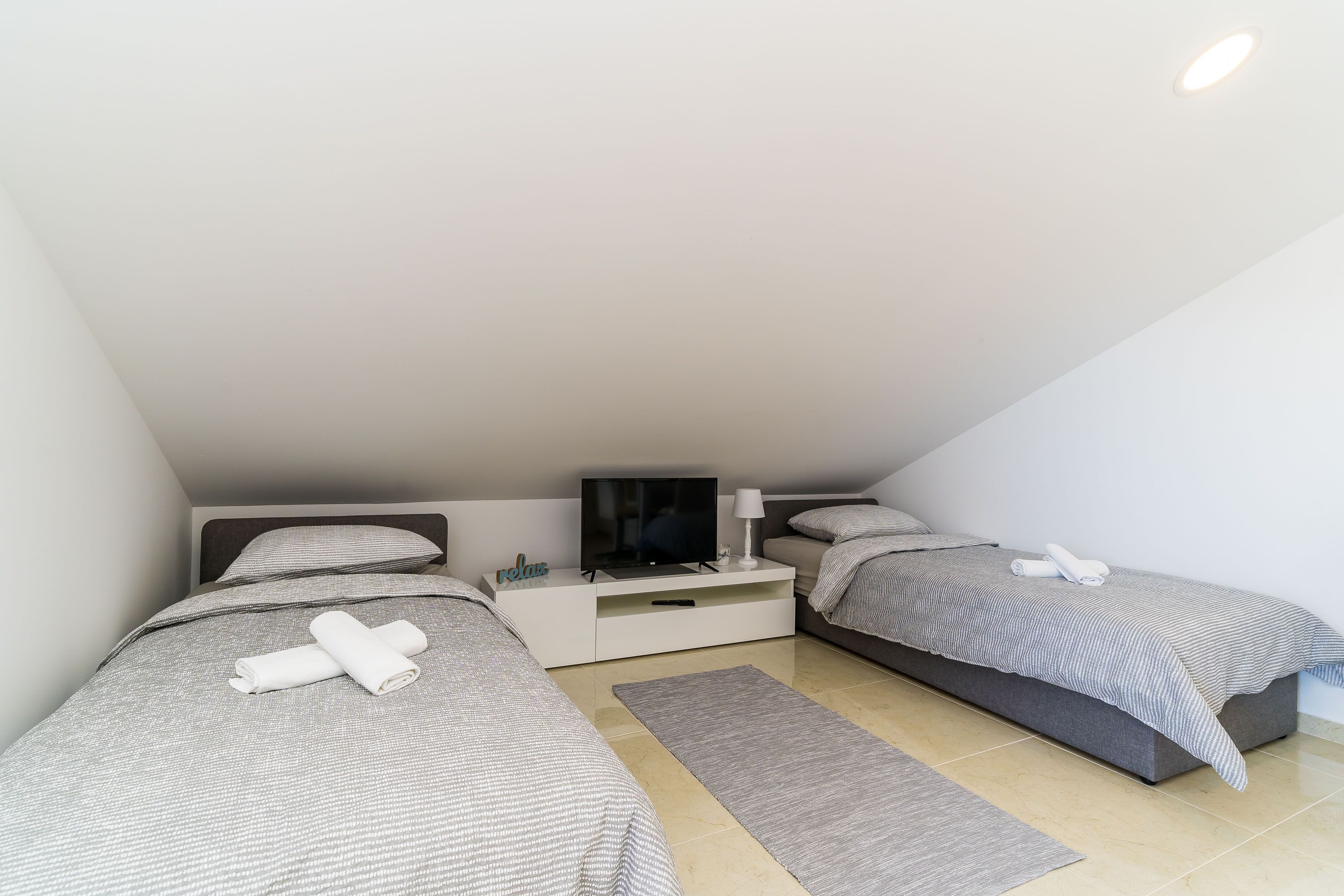 Ein modernes Schlafzimmer mit zwei Betten, einem Fernseher und einem Nachttisch.