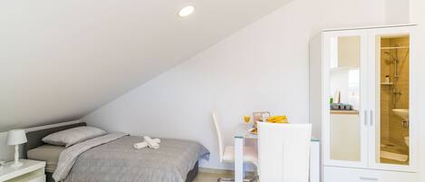 A bedroom with a bed, bedside table, chair, desk, and wardrobe.