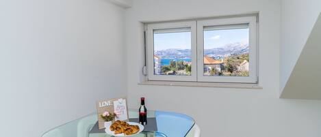 Une pièce moderne avec une table en verre, des chaises blanches, une bouteille de vin et un panneau sur lequel on peut lire le mot « AMOUR ».