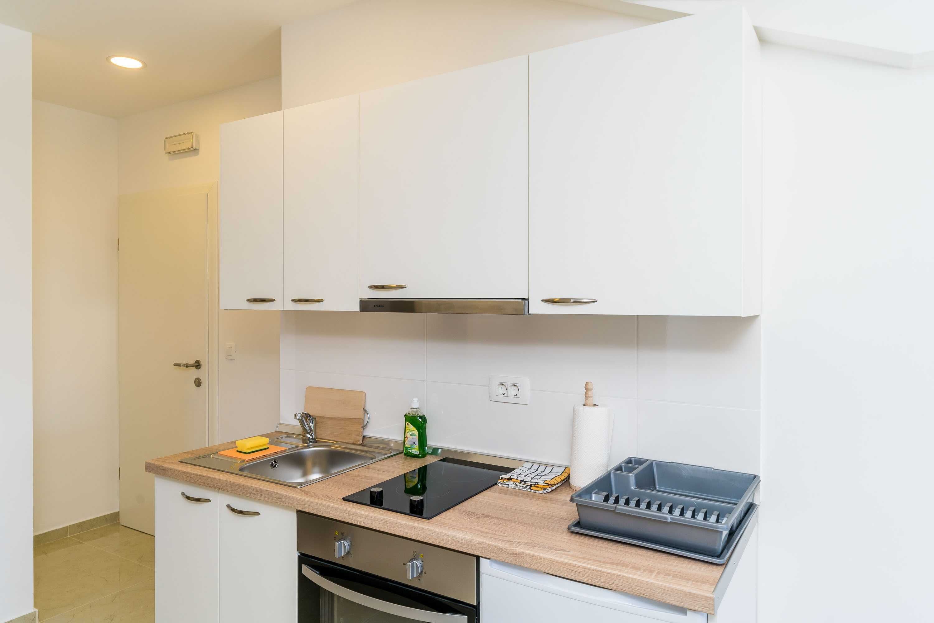 A modern kitchen with white cabinets, a stainless steel sink, and a black countertop.
