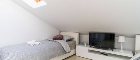 Un dormitorio moderno con una cama, un televisor, una mesita de noche y un ventanal.