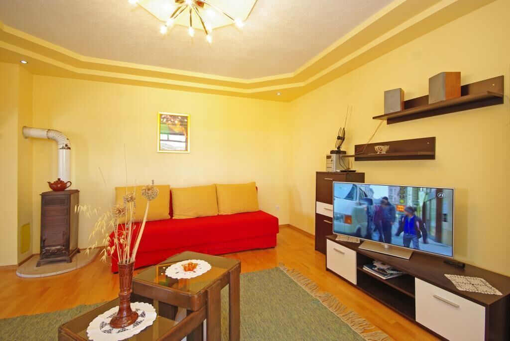 Een woonkamer met een rode bank, een televisie en een kleine tafel met een vaas.