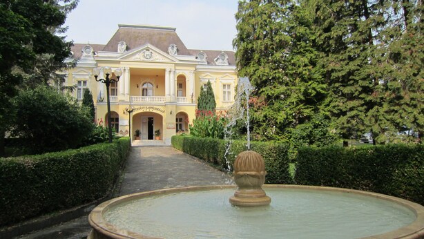 Ein prachtvolles Gebäude mit zentralem Eingang, einem Brunnen und gepflegten Hecken.