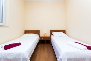 Two single beds with wooden headboards, a bedside table, and a lamp.
