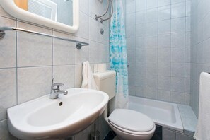 Bathroom features a pedestal sink, toilet, and shower area with a shower curtain.