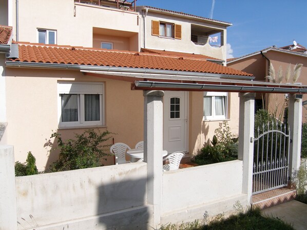 A two-story building with a tiled roof, a white door, and a small balcony.