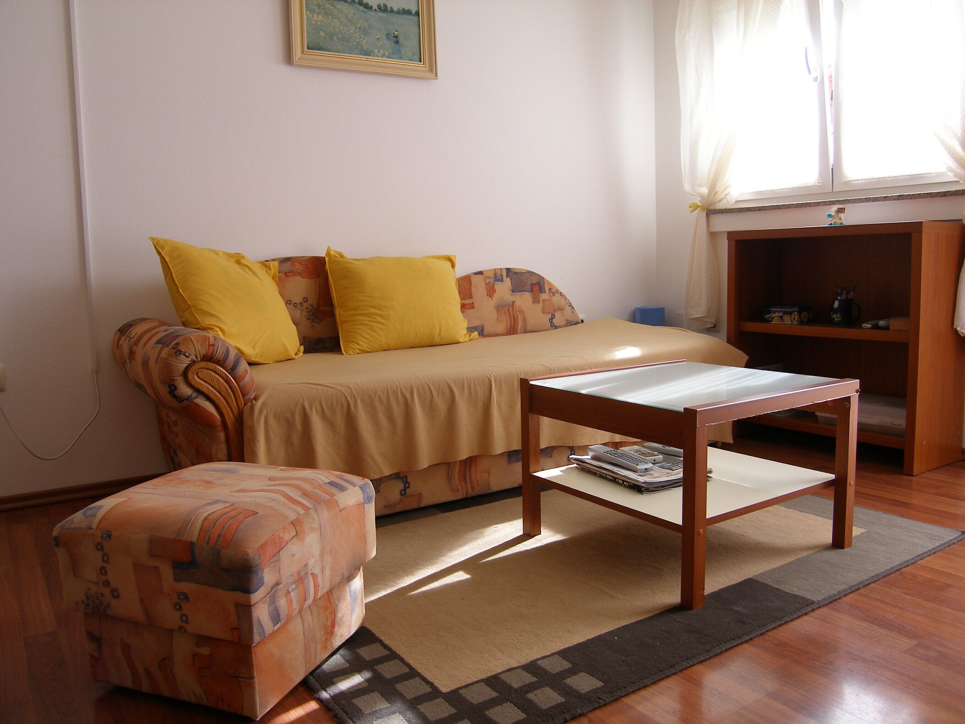 A cozy room with a sofa, a small table, and a patterned ottoman.