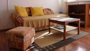 Een knus ingerichte kamer met een bank, een klein tafeltje en een gestreept voetenbankje.
