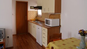 Een praktische keuken met houten kastjes, een magnetron en een eethoek met een tafel en stoelen.