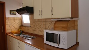 Een kleine keuken met houten kastjes, een magnetron en een spoelbak.