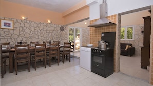 A kitchen with a dining area, stone wall, and a view of the outdoors. - Holiday Home Ivas (Milna)